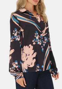 Kwiatowa bluzka na ciemnym tle, z różowymi i niebieskimi wzorami. Długie rękawy z guzikami i kołnierzykiem. Lekki materiał.