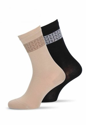 Beige en zwarte enkelsokken met patronenbanden bovenaan, met een herhaald geometrisch ontwerp, één achter de ander weergegeven.