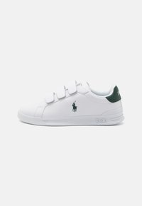 Weißer Sneaker mit Klettverschlussriemen, grünen Akzenten an der Ferse und grünem Logo an der Seite. Glatte Textur, Gummisohle und runde Zehenform.