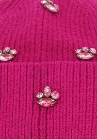Beanie lavorato a maglia fucsia con stampe di zampe di strass rosa decorative. Design a coste testurizzato e accenti lisci e lucidi sulla parte anteriore.
