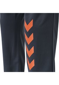 Pantalon de sport bleu marine avec un motif chevron orange sur le côté, confectionné dans un matériau lisse et respirant avec une coupe fuselée.