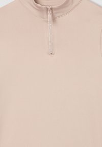 Jasnoróżowa bluzka z długim rękawem, uszyta z gładkiego materiału, z wysokim kołnierzem i półzamkiem z przodu.