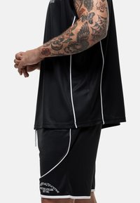 Zwart sportoutfit met een t-shirt met korte mouwen en witte accenten, gecombineerd met bijpassende shorts. Gemaakt van ademend materiaal, geschikt voor sport.