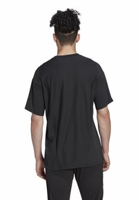 T-shirt noir à manches courtes avec un col arrondi. Texture lisse et coupe décontractée, avec des coutures discrètes et un dos légèrement plus long.