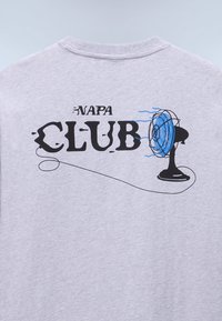 Dos d'une chemise grise avec texte noir "NAPA CLUB" et un ventilateur électrique noir soufflant des ondes d'air bleues vers la droite du texte.