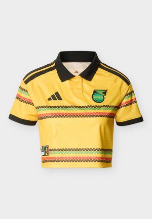 Žltý krátky futbalový dres s čiernym golierom a manžetami, erbom Jamajského futbalového zväzu, čiernym logom Adidas a viacfarebnými vodorovnými pruhmi.