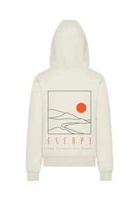 Haut à capuche crème avec un grand graphique représentant des montagnes, un soleil et le texte "ÉCHAPPER ET DÉCOUVRIR LE MONDE" en contours orange et noir.