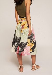 Floral skirt featuring vibrant colors, pleated design, elastic waistband, and detailed patterns with contrasting sections and polka dots.