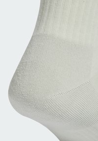 Calcetín blanco con textura acanalada que muestra detalles de costura distintivos. El material parece suave y elástico, diseñado para brindar comodidad.