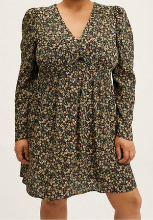 Femme portant une robe noire à manches longues, col en V, avec une taille froncée et un motif de petites fleurs multicolores.