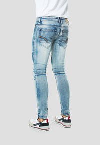 Niebieskie jeansy z denimu w wyblakłym odcieniu, o dopasowanym kroju, z dwoma tylnymi kieszeniami, detalami przeszyć oraz delikatnym przetarciem na kolanach.