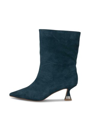 Stivale alla caviglia in suede navy scuro con punta affilata e un accento metallico unico sul tacco kitten. Texture morbida e design strutturato.