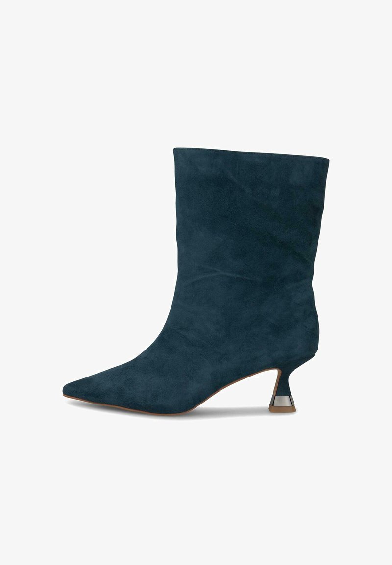 Botín de ante en azul marino oscuro con punta afilada y un acento metálico único en el tacón kitten. Textura suave y diseño estructurado.