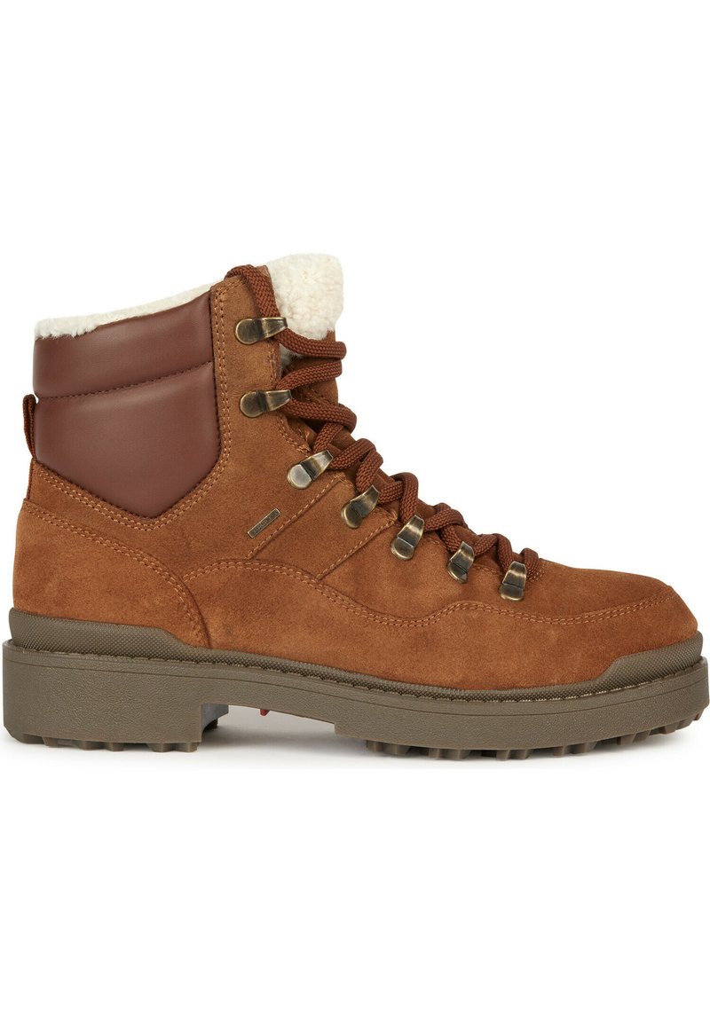 Botte de randonnée en suède marron avec une cheville en cuir beige, doublure en fausse fourrure, œillets en métal, lacets marron et semelle robuste pour l'adhérence.