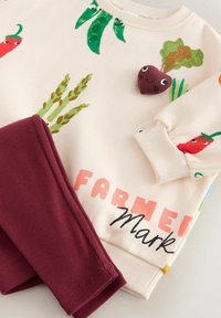 Jasnoróżowy bawełniany sweatshirt z nadrukami warzyw oraz bordowe prążkowane legginsy. Posiada małą pluszową dekorację buraka oraz tekst.