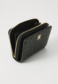 Portefeuille noir texturé avec fermeture éclair dorée et logo. Comprend plusieurs compartiments pour cartes et billets. Design rectangulaire élégant.