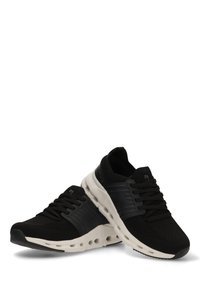 Zapatillas deportivas negras con parte superior de tejido de punto, cordones elásticos y una suela blanca acolchada con recortes circulares para ventilación.