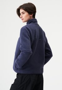 Marineblauer Fleece-Pullover mit hohem Kragen, strukturierter Stoff und kontrastierender schwarzer Rückseite. Lässige Passform mit großzügigen Ärmeln.