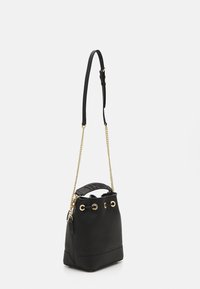 Sac seau en cuir noir avec quincaillerie dorée, sangle ajustable et finition texturée. Présente des accents œillets et une base plate pour plus de stabilité.