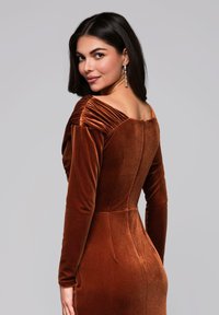 Robe en velours marron avec manches longues et silhouette ajustée. Détails plissés aux épaules et dos en encolure dégagée.