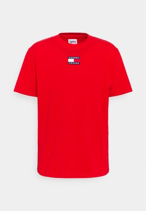 T-shirt rouge à manches courtes et col rond avec un petit patch rectangulaire du logo Tommy Jeans centré sur la poitrine.
