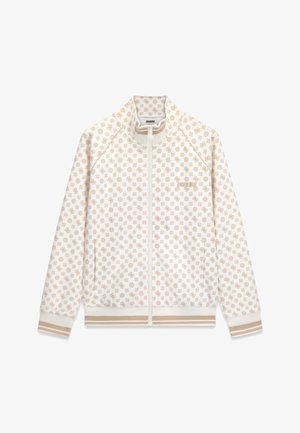Veste blanche zippée avec un motif logo beige répété, des poignets et un bas côtelés avec des rayures beiges, et le texte "GUESS" sur la poitrine gauche.