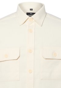 Crème-kleurige button-up shirt gemaakt van textuurstof, met twee borstzakken en zachte, ronde knopen.