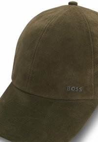 Gorra de ante verde oliva con visera curva, diseño de seis paneles y un pequeño logo plateado "BOSS" en el lado izquierdo. Textura suave en toda la superficie.