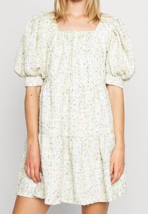 Robe avec manches courtes bouffantes et tissu lâche texturé dans un motif clair tacheté avec des accents bleus et verts.