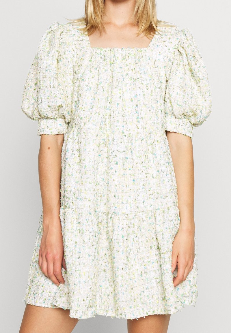 Robe avec manches courtes bouffantes et tissu lâche texturé dans un motif clair tacheté avec des accents bleus et verts.