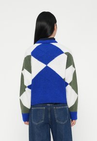 Strickpullover mit einem Rautenmuster in Blau, Weiß und Grün. Merkmale sind gerippte Bündchen und Saum, mit einer lockeren Passform und einem Kragen Design.