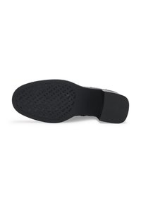 Semelle de chaussure habillée noire avec motif de grip texturé à l'avant-pied et talon lisse, inclinée pour montrer la vue complète du dessous sur fond blanc.