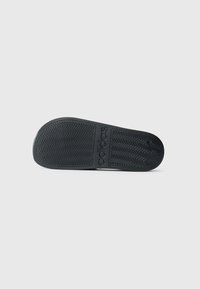 Sort gummisål til sneakers med fiskenets mønster og indgraveret logo. Glat tekstur med rund tå og let hævet hæl.