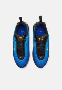 Pair of blue and black Nike Air sneakers with yellow swoosh logos, viewed from above on a white background.