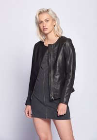 Schwarze Lederbomberjacke mit rundem Ausschnitt, Frontreißverschluss, gerippter Textur und kontrastierenden Stoffakzenten an den Ärmeln.