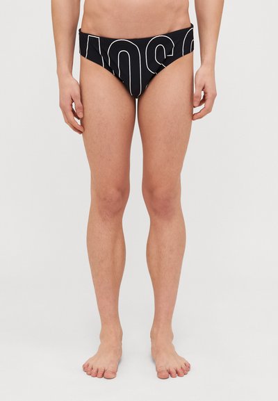 Schwarze Schwimmslips mit boldweißer Schrift. Der Stoff ist glatt, mit einem niedrigen Schnitt und minimaler Abdeckung, entworfen für Komfort.