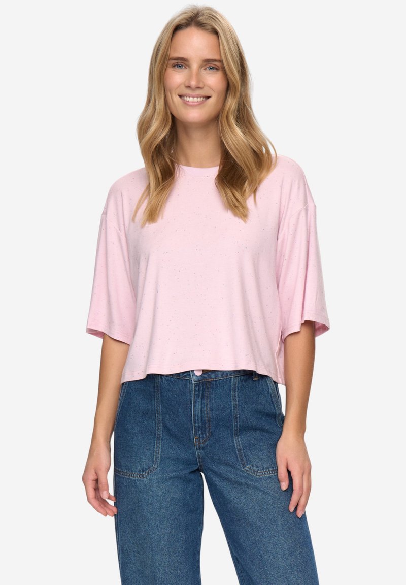 T-shirt rose clair court en tissu doux avec un col rond et des manches courtes larges. Porté avec un jean taille haute en denim.