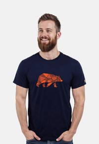 Navyblaue Baumwoll-T-Shirt mit einem geometrischen orangefarbenen Bärenmotiv auf der Vorderseite. Kurze Ärmel und Rundhalsausschnitt.