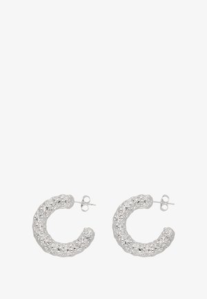 Boucles d'oreilles en argent en forme de créoles avec une surface texturée, présentant des motifs complexes et des formes arrondies, fixées avec une attache à clou.