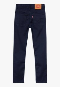 Vaqueros de mezclilla azul oscuro con corte slim, que cuentan con dos bolsillos traseros, detalles de costura sutil y una etiqueta de cuero en la cinturilla.