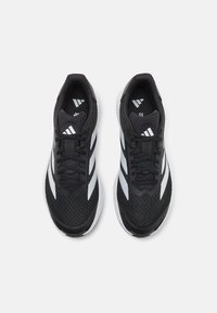 Black athletic shoes with a textured upper, featuring white stripes on the sides, round toe, and a cushioned sole for comfort.