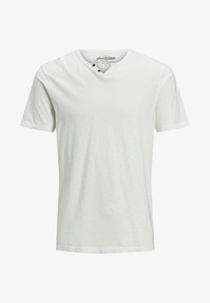 T-shirt blanc à manches courtes avec un tissu texturé, présentant un col en V et deux boutons décoratifs près du col.