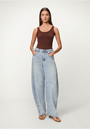 Brun ermeløs topp kombinert med lyseblå, vidbente jeans i denim med frontlommer og slitte detaljer. Brukt med brune sandaler.