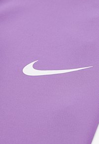 Fialová sportovní tkanina s texturovaným vzorem. Obsahuje výrazné bílé logo Nike ve tvaru swoosh. Odolný a lehký materiál.