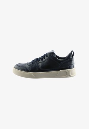 Navy leather sneaker featuring a low-profile design, perforated toe, and a beige rubber sole with subtle accents and textured finish.