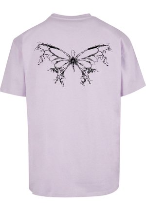 Lila bomullströja med en svart fjärilsdesign på baksidan, omgiven av flytande, stänk-liknande detaljer. Korta ärmar, rund nacke.