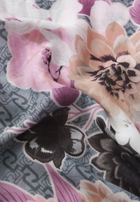 Tessuto floreale con grandi fiori rosa e neri su uno sfondo grigio con un motivo sottile. Morbida texture con caduta fluida.