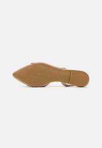 Zapato de tacón alto color tostado con punta afilada y suela de goma texturizada, que presenta surcos para tracción y un acabado suave en la parte superior.