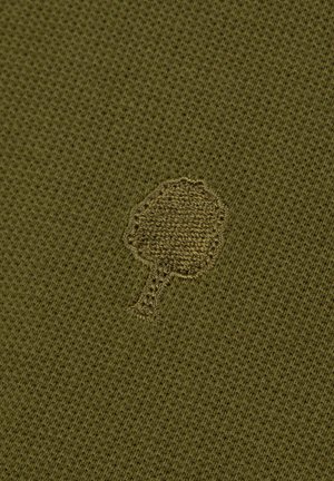 Icône d'arbre brodé sur un tissu tricoté à texture vert olive.