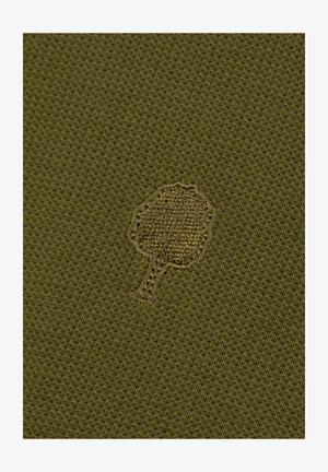 Gesticktes Baum-Icon auf olivgrünem, strukturiertem Strickstoff.